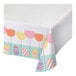 A white tablecloth with a pattern of colorful eggs and tulips.