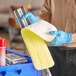 A gloved person holding a yellow and white Advantage Supplies microfiber cloth.