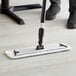 A person using a Lavex Microfiber wet mop to scrub a floor.