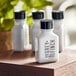 A group of small white Grey + Finch body lotion bottles with black lids on a table.
