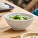 A white round melamine bowl filled with edamame.