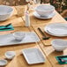 A set of light gray round melamine ramekins displayed on a wooden dining table with matching dinnerware.