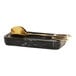 A black Cal-Mil swirl spoon rest with a gold spoon in it.