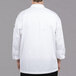 A man wearing a white Chef Revival long sleeve chef jacket with Chef logo buttons.