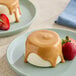 A serving of panna cotta or similar dessert topped with peanut butter sauce and garnished with strawberries on a plate.