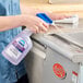 A person spraying Dawn Professional kitchen surface degreaser onto a stainless steel surface.