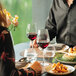 A man and woman holding Arcoroc Serena wine glasses filled with red wine at a table.