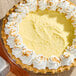 A coconut cream pie with a creamy yellow filling, topped with whipped cream and toasted coconut flakes around the edge.