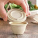 A compostable fiber lid being placed on a small fiber portion cup.