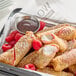 A tray of raspberry cheesecake dessert egg rolls dusted with powdered sugar, served with fresh raspberries and a side of chocolate dipping sauce.