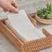 A stack of linen-feel flower-patterned guest towels in a woven basket.