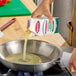 A carton of Papetti's Liquid Egg Whites being poured into a stainless steel frying pan on a stove.