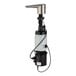 A Bobrick brushed nickel automatic liquid soap dispenser on a white and black sink.