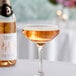 A coupe glass filled with sparkling rosÃ©, with a bottle of Noughty Non-Alcoholic Sparkling RosÃ© in the background.