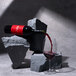 A red and black Noughty Non-Alcoholic Rouge Syrah bottle of wine being poured into a glass.