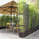 A tall terra resin modular partition with a grid design and integrated self-watering planter, used for outdoor space separation and plant display.
