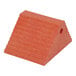 A large orange plastic dual slope wheel chock with a ridged surface and a hole on one side.