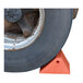 A large orange plastic dual slope wheel chock positioned against a vehicle tire.