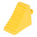 A yellow polyethylene wheel chock with a handle and a ridged surface.