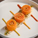 A plate of rolled carrot tagliatelle arranged in a decorative presentation with sauces and garnish.