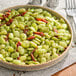 A plate of cooked lima beans mixed with herbs and sun-dried tomatoes.