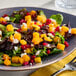 A plate of salad featuring IQF diced butternut squash, mixed greens, pomegranate seeds, and crumbled cheese.