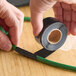A roll of clear self-fusing silicone rubber electrical tape being wrapped around a green cable.