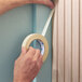 A roll of general purpose masking tape being applied to a surface.