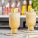 Two glasses of yellow lemon cocktails with lemon slices and straws.