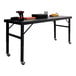 A large black mobile adjustable height work table with tools and supplies on top.