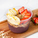 A bowl of Pitaya Foods Organic Acai Sorbet topped with banana and strawberries on a wooden tray.