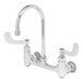 A silver T&S wall mounted surgical sink faucet with 4" wrist action handles.