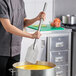 A long stainless steel paddle being used to stir a large pot in a commercial kitchen.