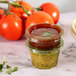 A couple of Eco-Products compostable green PLA plastic portion cups filled with sauce next to tomatoes.