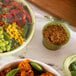 Eco-Products WorldView compostable flat lid on a table with bowls of food.