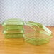 A group of Eco-Products green plastic containers with lids on a wood surface.