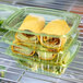 A stack of Eco-Products rectangular green plastic deli containers filled with food on a shelf.