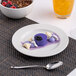 A white round embossed wide rim flat porcelain plate with a dessert served on it.