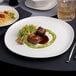 A close up of food on an Ariane Earth porcelain plate on a table.