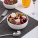 A white embossed porcelain bowl filled with salad, placed on a woven placemat.
