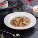A white round embossed wide rim deep porcelain plate with a 9-inch diameter.