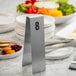 A silver stainless steel table tent with the number 8 printed in black.