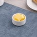 A small round white porcelain ramekin containing several cubes of butter.