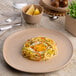 An Ariane Earth porcelain plate with spaghetti and an egg on it.