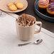 A dark sand dots porcelain mug filled with hot chocolate and marshmallows on a table in a bakery display.