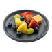 A speckled gray round melamine plate with assorted fresh fruit pieces.
