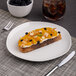 A Ariane Earth porcelain plate with a piece of bread and blackberries on it.