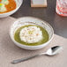 A table with two Ariane white slanted bowls filled with rice and green soup.