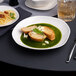 An Ariane Earth porcelain plate with food on a table.