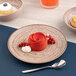 An Ariane Tornado round rimless porcelain plate with a cupcake with blue frosting and a blueberry on top.